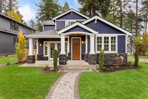 A photo of the front of a home with a stone custom walkway leading through the yard to the front door.
