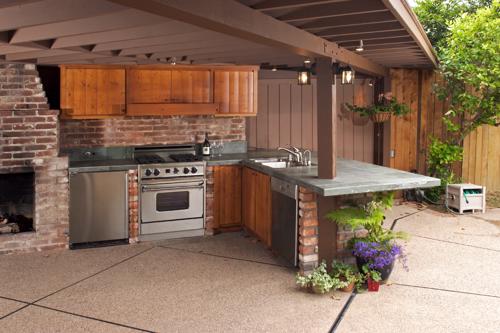A shaded outdoor kitchen in a back yard.